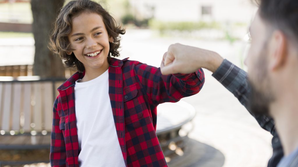 smiley boy knocking fist with his father while outdoors